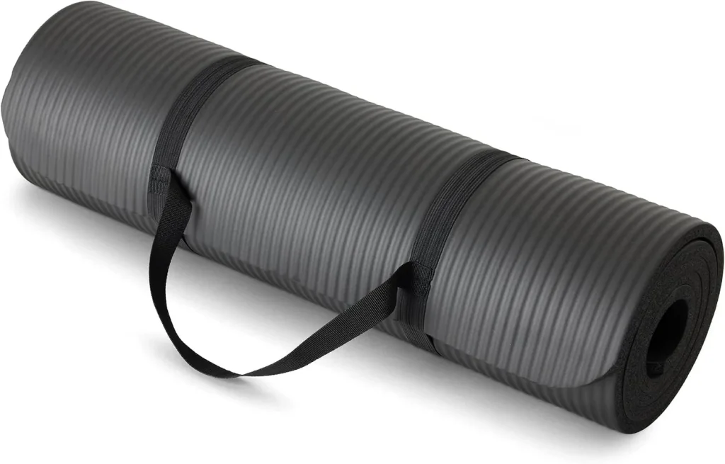 The Amazon Basics extra thick mat in black sits rolled with its carrying strap wrapped around the foam.