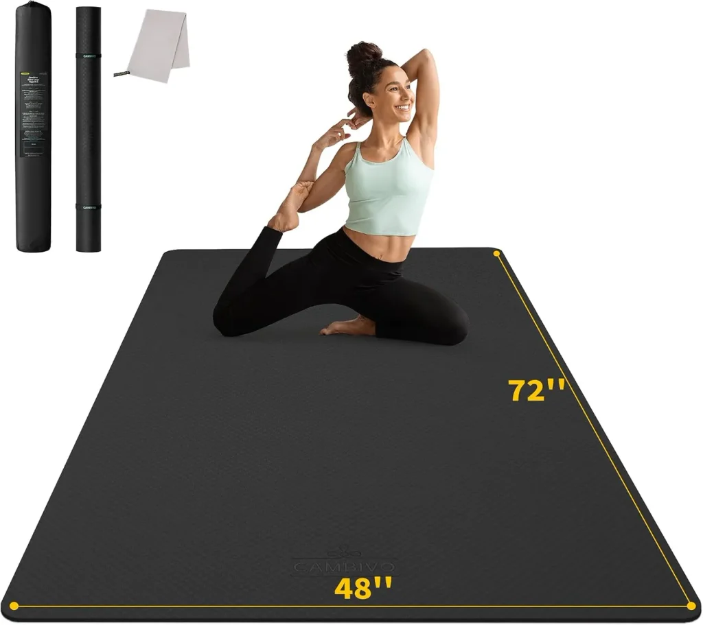 A yogi sits cross legged on the black CAMBIVO extra wide mat showing its generous seventy two by forty eight inch surface.
