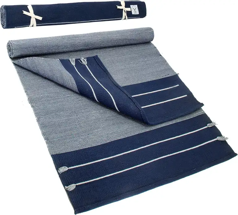 Handwoven cream cotton yoga rug with woven border, folded for travel.