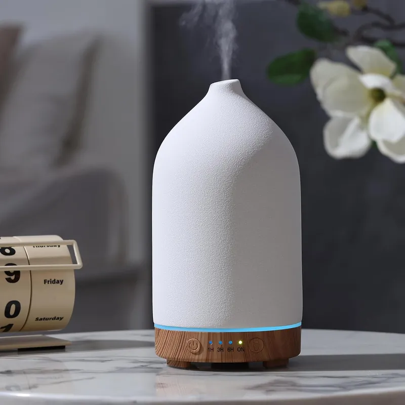 matte white bottle shaped diffuser on wood base with blue light ring