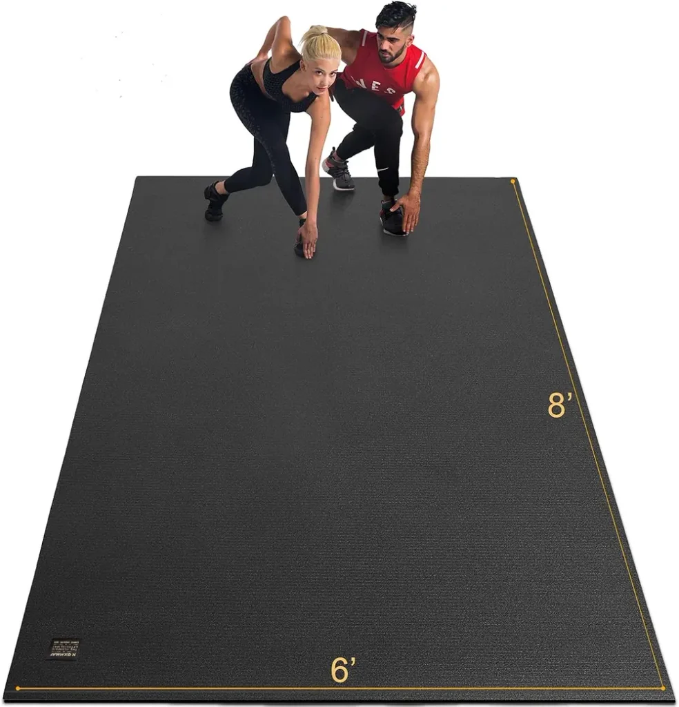 The GXMMAT extra large exercise mat in grey sits partially rolled ready to unroll across a home gym.