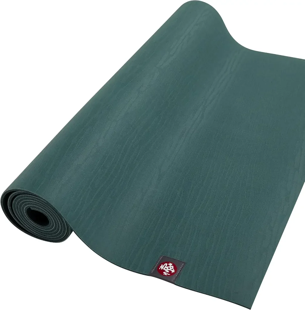 The Manduka eKO Lite yoga mat in deep sea lies flat with one end curled up showing its textured rubber surface.