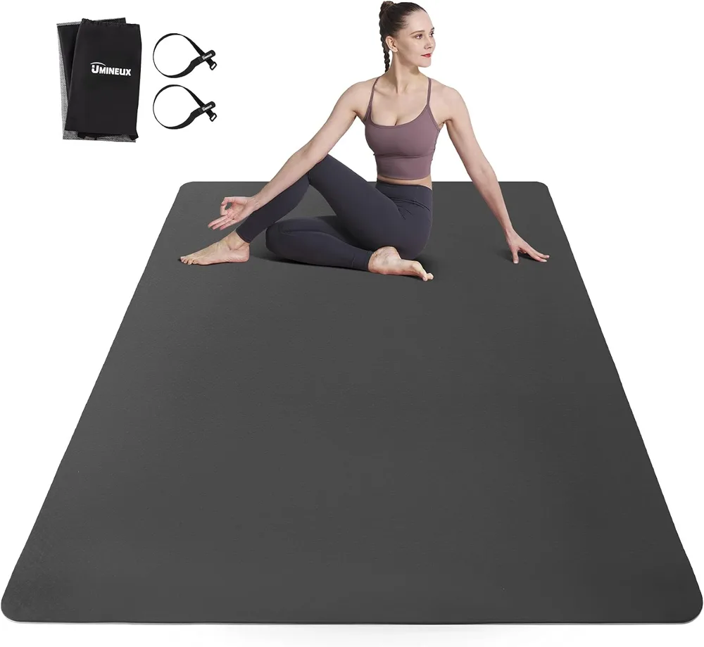 The UMINEUX large yoga mat in black and grey two tone with its storage bag and straps laid out.